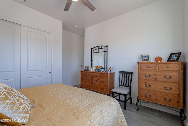 bedroom featuring a ceiling fan, a closet, baseboards, and wood finished floors