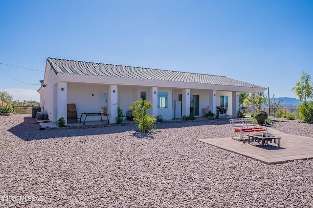 rear view of house featuring stucco siding, a tile roof, fence, and a patio