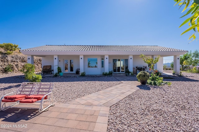 rear view of property with a tiled roof, french doors, and stucco siding