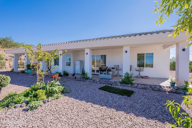 rear view of house featuring a patio area and stucco siding