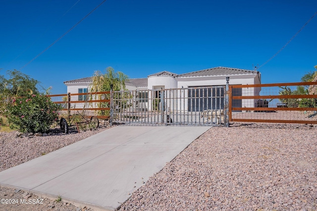 view of front of property featuring stucco siding, a fenced front yard, a gate, and a tile roof