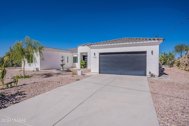 view of front of property featuring driveway, a tiled roof, an attached garage, and stucco siding