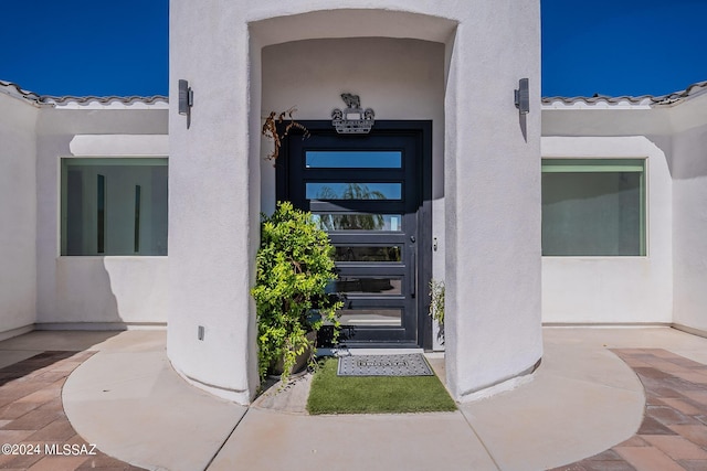 property entrance with a tiled roof and stucco siding