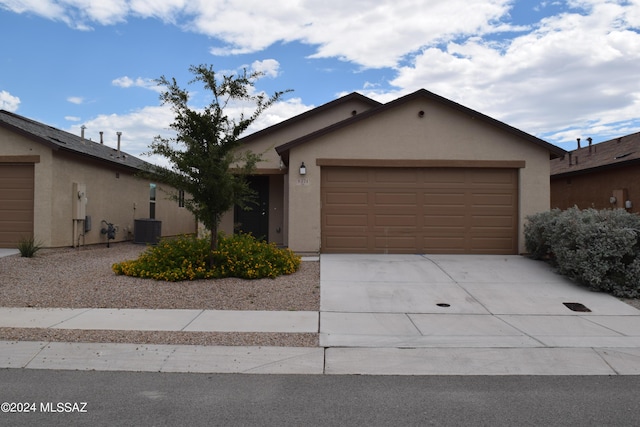 view of front of home with driveway, a garage, central AC unit, and stucco siding