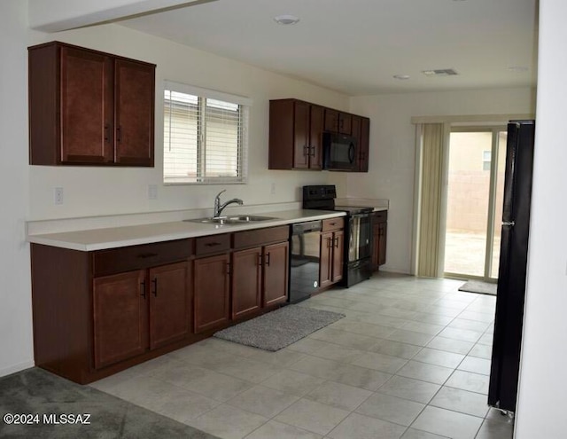 kitchen with light tile patterned flooring, plenty of natural light, sink, and black appliances