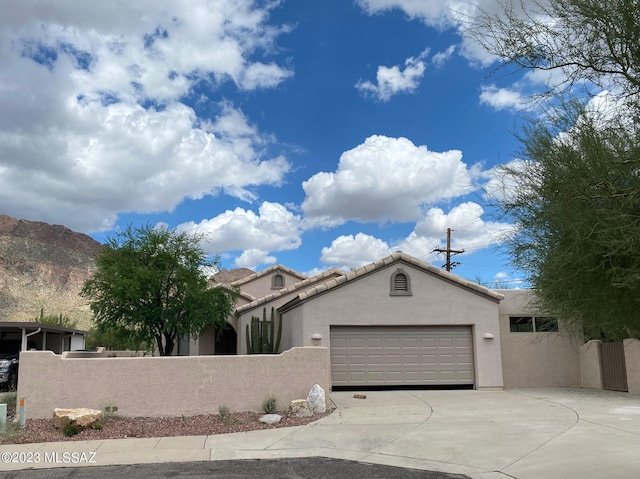 view of front of home with a garage, concrete driveway, a fenced front yard, a tile roof, and stucco siding