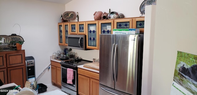 kitchen featuring stainless steel appliances, light countertops, glass insert cabinets, and light tile patterned floors