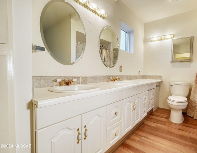 bathroom with wood-type flooring, dual vanity, and toilet