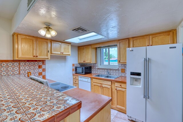 kitchen featuring white appliances, tile counters, light tile patterned flooring, sink, and light brown cabinets