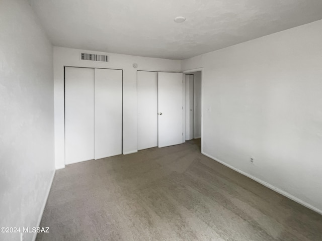 unfurnished bedroom featuring two closets and carpet floors