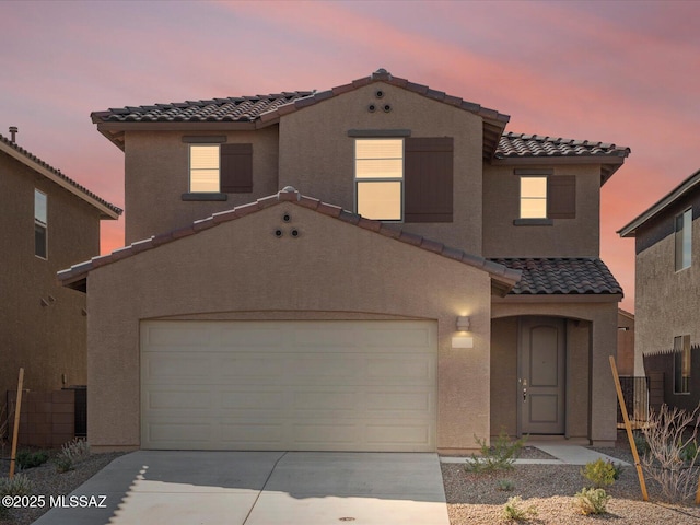 mediterranean / spanish house featuring stucco siding, concrete driveway, and a tile roof