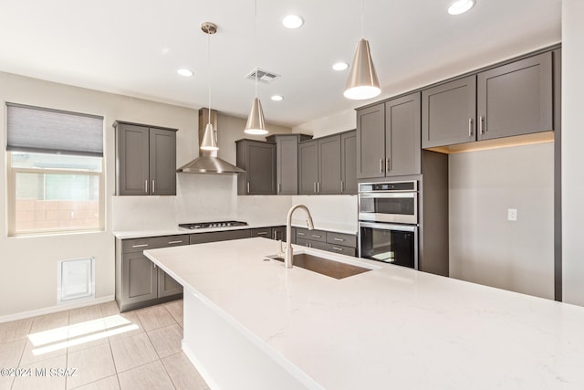 kitchen with light tile patterned flooring, sink, double oven, wall chimney exhaust hood, and pendant lighting