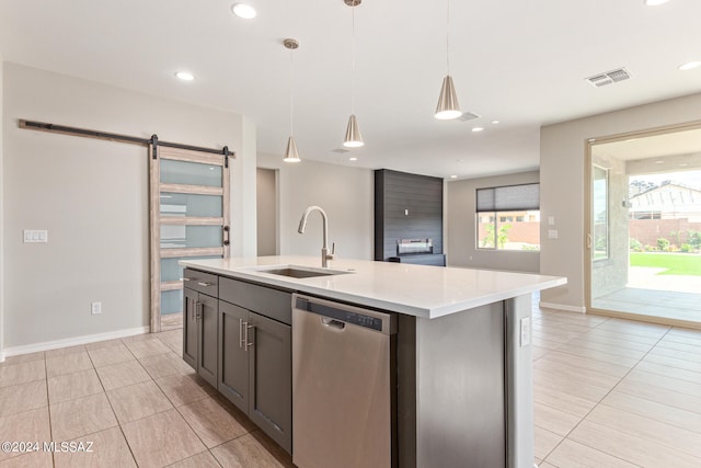 kitchen featuring dishwasher, sink, a kitchen island with sink, light tile patterned floors, and a barn door