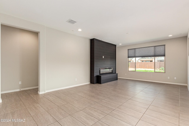 unfurnished living room featuring a large fireplace and light tile patterned floors