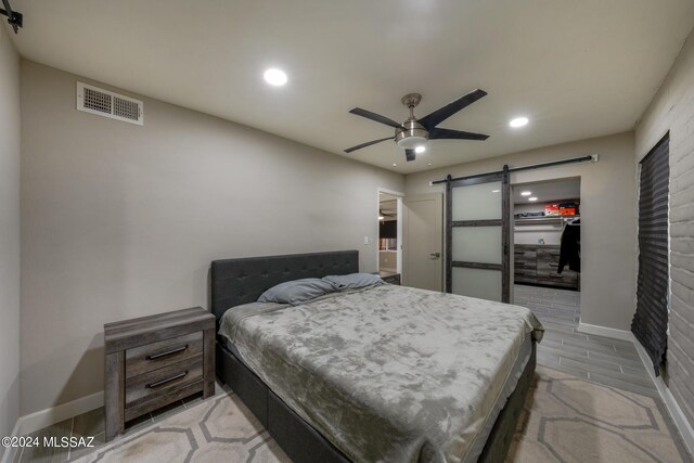 bedroom featuring ceiling fan and a barn door