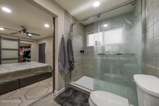 bathroom with ceiling fan, tile patterned flooring, toilet, and a shower with door