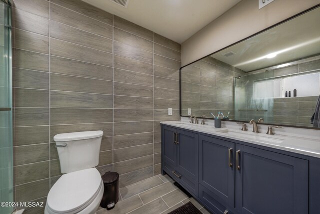 bathroom with tile walls, toilet, vanity, and walk in shower