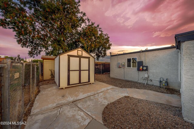 back house at dusk featuring a storage unit and a patio area