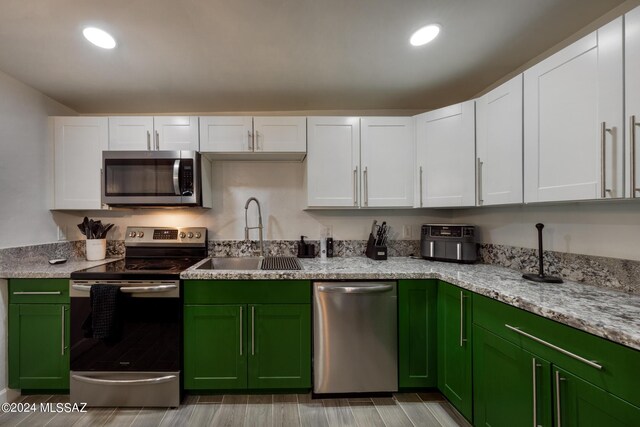 kitchen with white cabinetry, sink, stainless steel appliances, and green cabinetry