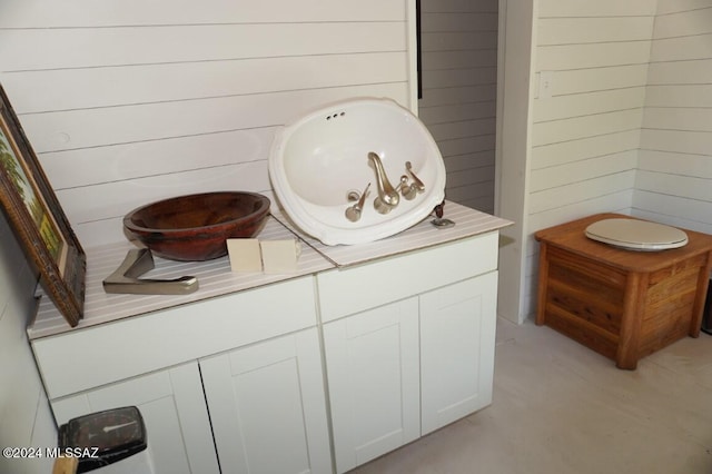 bathroom with vanity, wood walls, and concrete floors