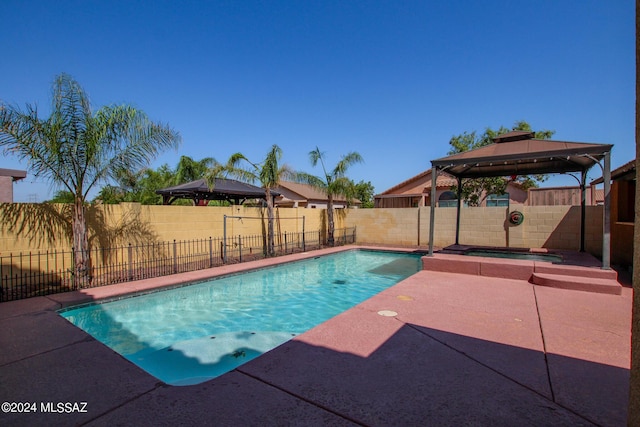 view of swimming pool with a fenced backyard, a pool with connected hot tub, and a gazebo