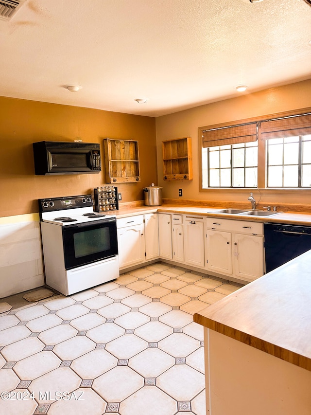 kitchen featuring a textured ceiling, light tile patterned floors, sink, black appliances, and white cabinets