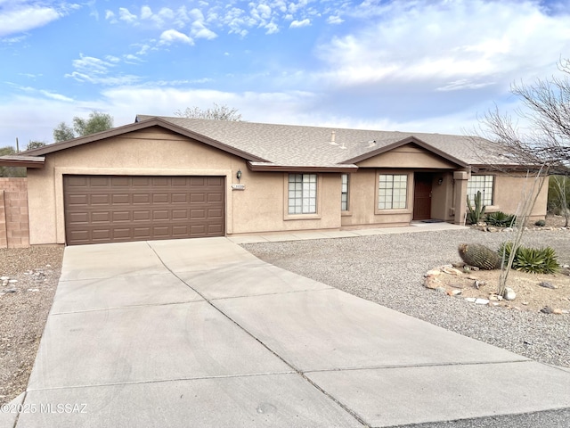 ranch-style house with driveway, a shingled roof, an attached garage, and stucco siding