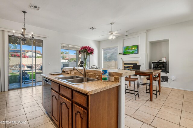 kitchen with a kitchen island with sink, ceiling fan with notable chandelier, sink, stainless steel dishwasher, and decorative light fixtures