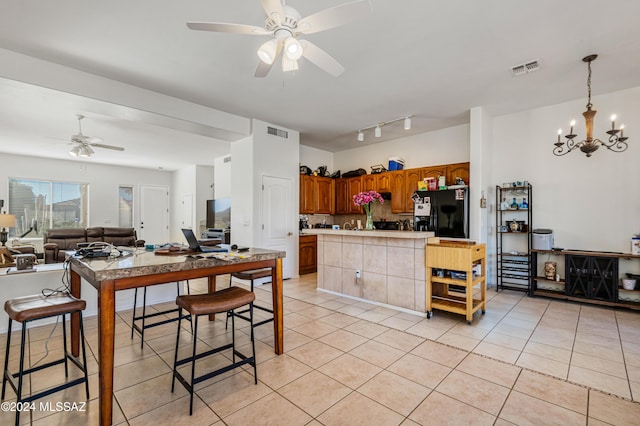 kitchen with backsplash, black refrigerator with ice dispenser, ceiling fan with notable chandelier, light tile patterned floors, and decorative light fixtures