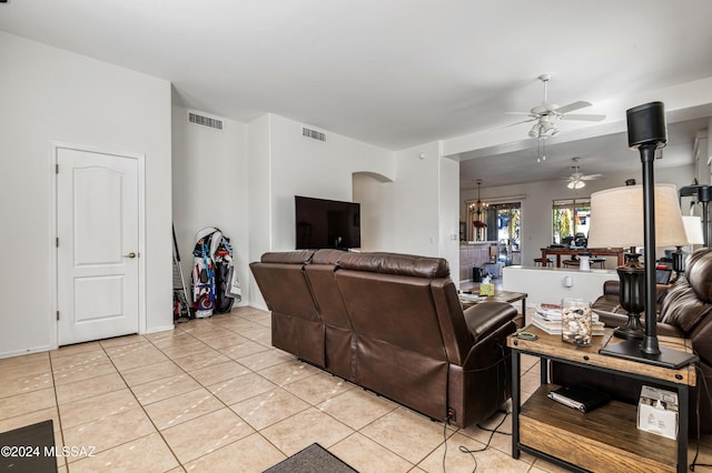 tiled living room with ceiling fan with notable chandelier