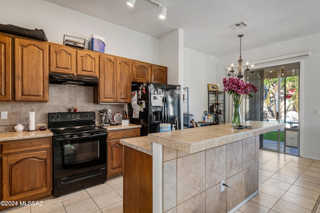 kitchen featuring black appliances, decorative light fixtures, an inviting chandelier, a kitchen island, and light tile patterned flooring