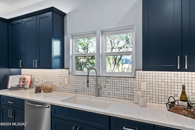 kitchen featuring stainless steel dishwasher, backsplash, blue cabinetry, and sink