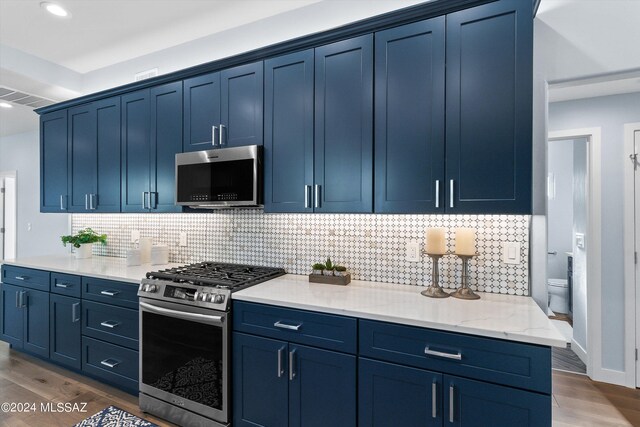 kitchen with tasteful backsplash, blue cabinets, dark hardwood / wood-style floors, and appliances with stainless steel finishes