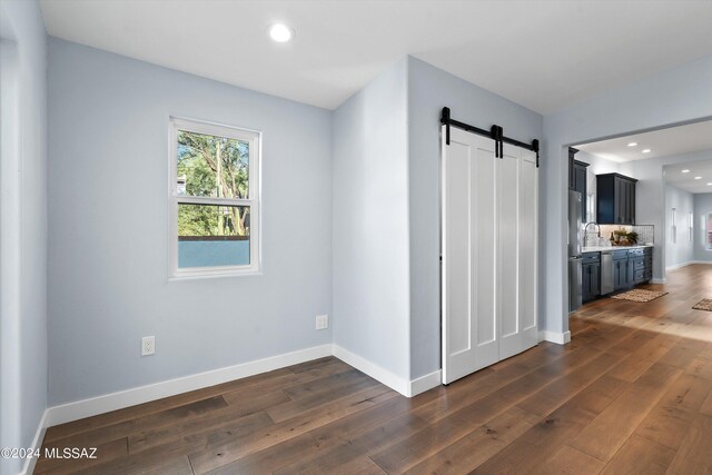 spare room with dark hardwood / wood-style flooring, a barn door, and sink