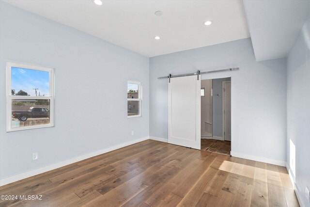 spare room with a barn door and hardwood / wood-style flooring