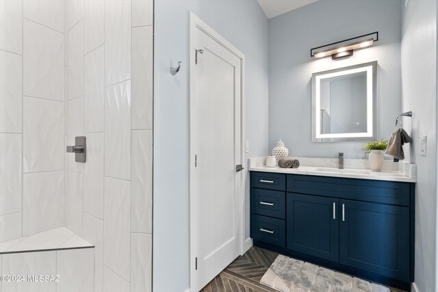 bathroom featuring a shower, vanity, and parquet floors