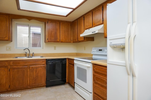 kitchen featuring under cabinet range hood, light countertops, brown cabinets, white appliances, and a sink