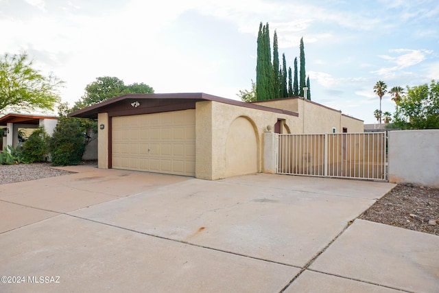 view of front of property with a gate, a garage, driveway, and stucco siding