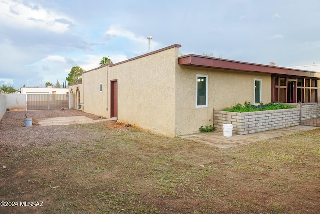 rear view of property with stucco siding and fence