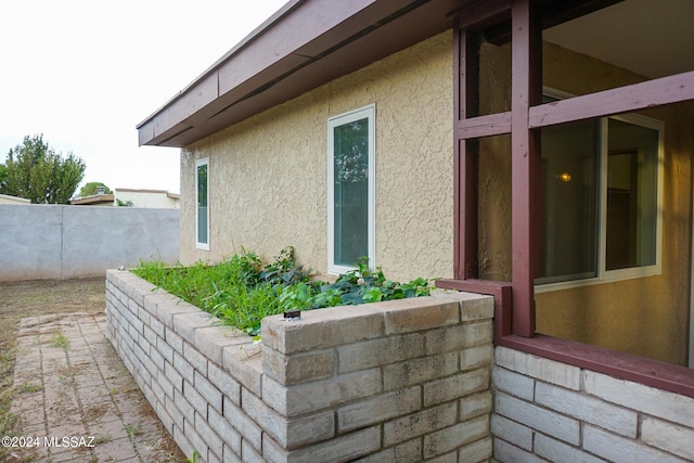 view of side of property with stucco siding and fence