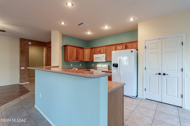 kitchen with light tile patterned floors, kitchen peninsula, and white appliances