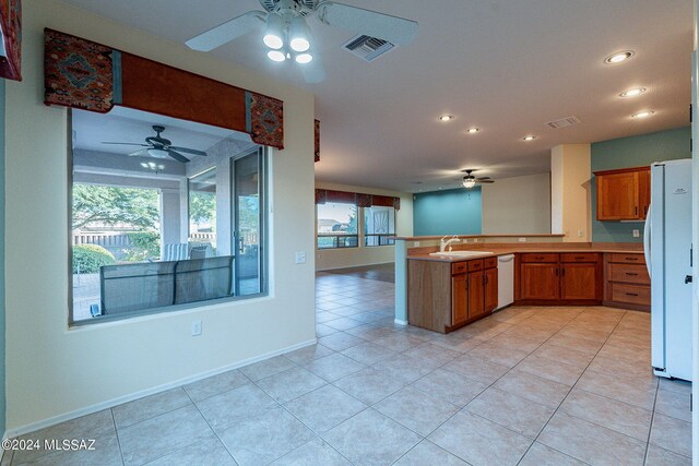 kitchen with ceiling fan, light tile patterned floors, kitchen peninsula, and white appliances