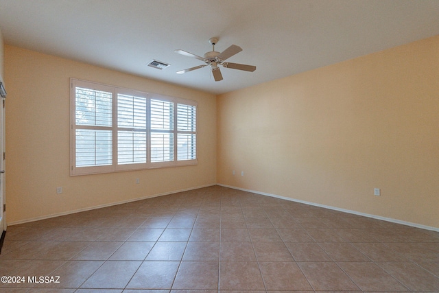 tiled spare room with ceiling fan