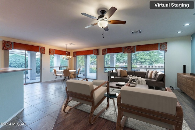 tiled living room with ceiling fan with notable chandelier and plenty of natural light