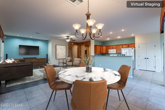 tiled dining space featuring ceiling fan with notable chandelier