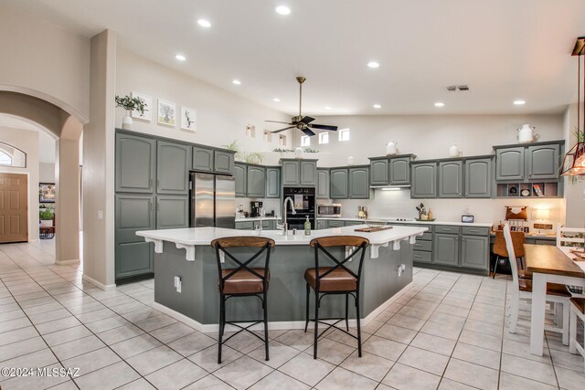 kitchen featuring a kitchen island with sink, stainless steel appliances, light tile patterned floors, and ceiling fan