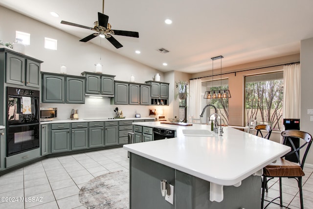 kitchen featuring an island with sink, vaulted ceiling, black appliances, pendant lighting, and sink