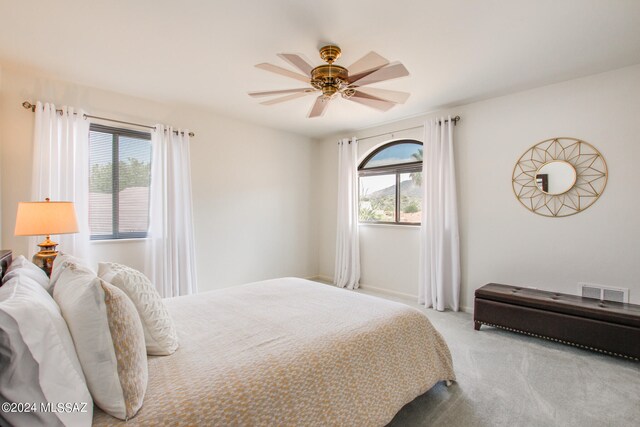 carpeted bedroom featuring ceiling fan and multiple windows