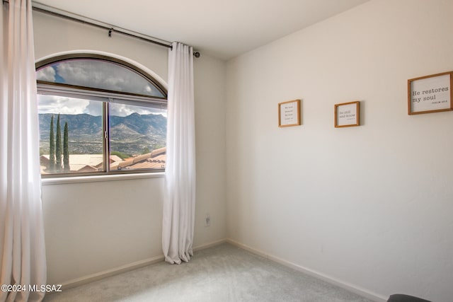 spare room with a mountain view and carpet floors