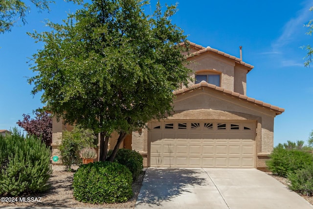 view of front of home with driveway, stucco siding, a tiled roof, and a garage
